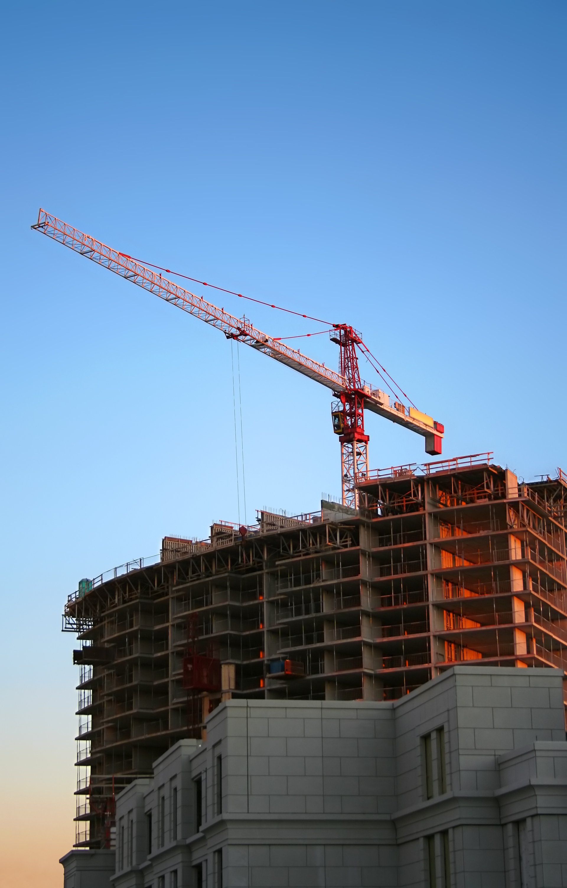 Une grue est posée au sommet d’un bâtiment en construction.